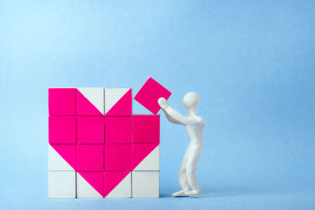 dice heart. a man of white plasticine puts the last die. concept of medicine, valentine's day...