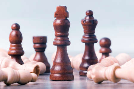 On the table are black chess pieces. The kingâ€™s figure is in focus in the center; the...