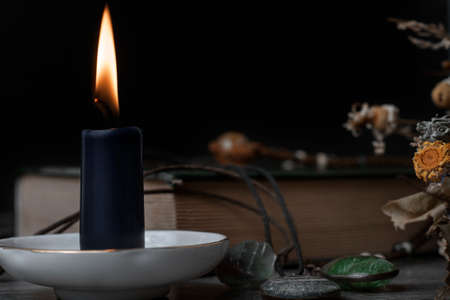 A burning candle, a book, dry herbs, and magic stones. Set for witches.の写真素材