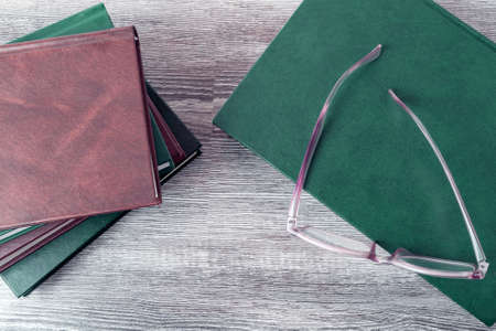 On the table is a book with glasses on it. Next to it is a stack of other books. World book day. The view from the top.の写真素材