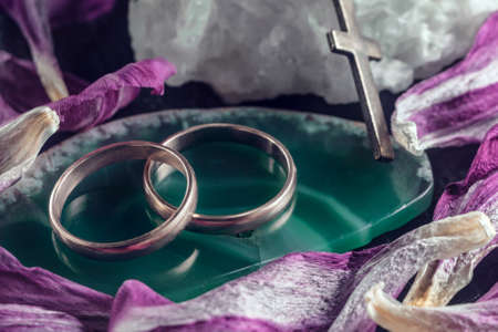 Two intertwined wedding rings on a green stone.の写真素材