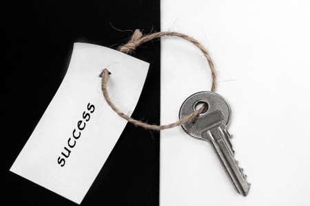 On a black-and-white background, a key with an inscription on the tag: "success".の写真素材