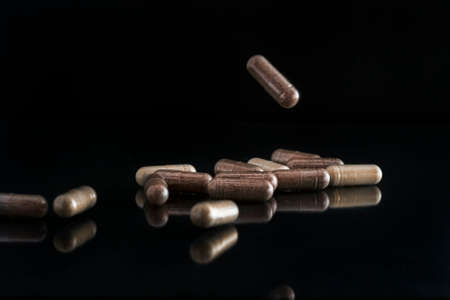 Concept of medicine, pharmacology, and medical care. On a dark background are pills. One of them...