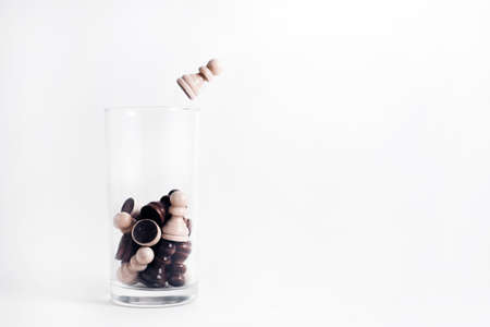 The concept of getting out of the comfort zone, success, motivational concept. On a white background, a glass Cup filled with chess pieces. A white pawn jumps out of the glass.の写真素材