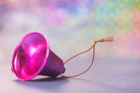 Picture of pink Christmas bell on multicolor background with spots. Selective focus.