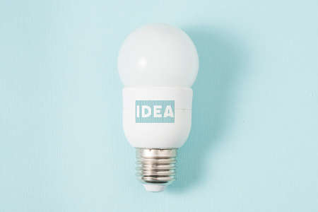 White energy-saving lamp on a blue background. On the lamp base there is an inscription in the form of a barcode ideaの写真素材