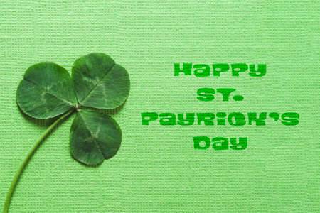 St. Patrick's day greeting card. On a textured green background, a clover Shamrock and the inscription happy St. Patrick's day.の写真素材