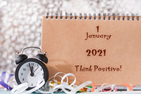 Motivational quote think positive. Retro alarm clock in a new year's environment next to an open...