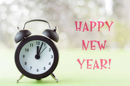 Happy new year greeting card. Retro alarm clock on the background of Christmas lights.