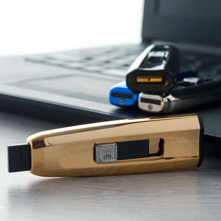 A yellow USB flash drive is on the table next to the laptop.の写真素材