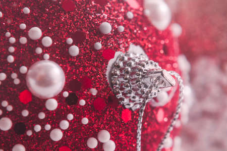 Macrophotography of the new year's red ball. The ball is decorated with white beads of different...