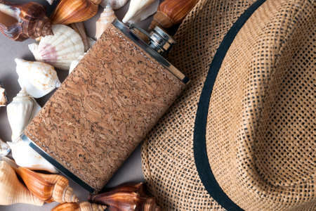 The flask for alcohol is lying on the scattered shells. Next to it is a men's vintage hatの写真素材