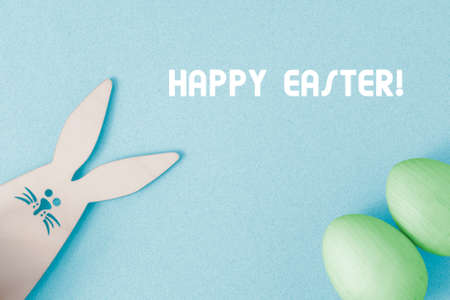 Happy Easter greeting card. On a blue background, congratulations on Easter. Bunny Rabbit peeks out...
