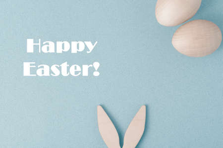 Happy Easter greeting card. On a blue background, congratulations on Easter. The rabbit's ears stick...