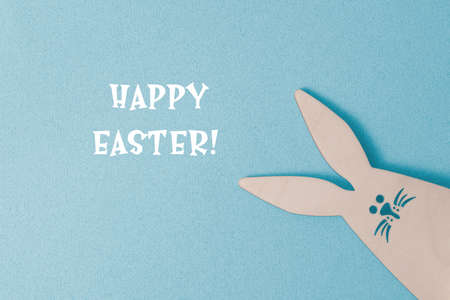 Happy Easter greeting card. On a blue background, congratulations on Easter. Bunny Rabbit peeks out from the bottom right cornerの写真素材