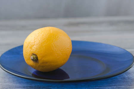 Yellow lemon on a blue glass plate.の写真素材