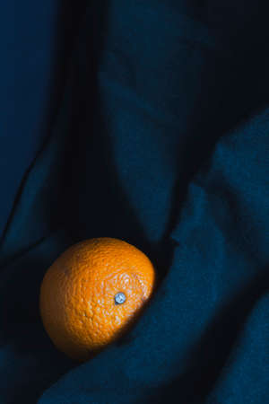 A ripe orange in the folds of a blue cloth. The concept of proper nutrition and a healthy lifestyle.の写真素材
