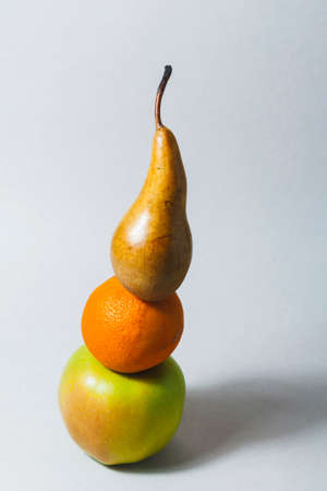 On a light background, a composition of three fruits. Apple, orange, and pear. The fruit forms a...