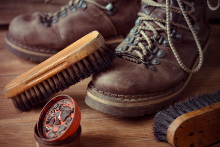 Old Vintage Leather Boots with Shoe Brush on Wooden Backgroundの写真素材