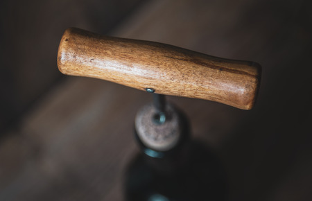 Bottle of wine with a corkscrew on blurry wooden backgroundの写真素材
