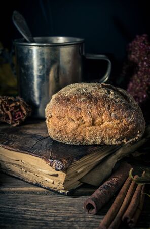 Steel cup of tea and a bun on a seasonal rustic background, close up still lifeの写真素材