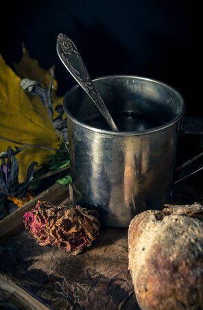 Steel cup of tea and a bun on a seasonal rustic background, close up still lifeの写真素材