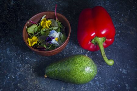 Green avocado, red pepper and fresh salad on rustic kitchen backgroundの写真素材