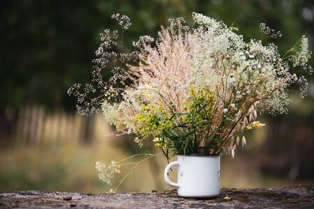 Beautiful field flowers, rural bouquet in white metal cup