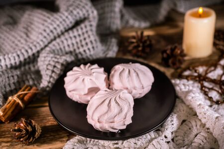 Homemade organic zephyr with candle and cinnamon sticks on rustic background. Pink marshmallow.の写真素材
