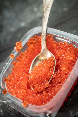 Fresh red caviar on spoon and piece of breadの写真素材