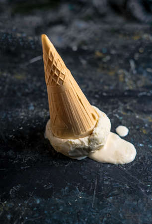 Fallen ice cream upside down on dark concreteの写真素材
