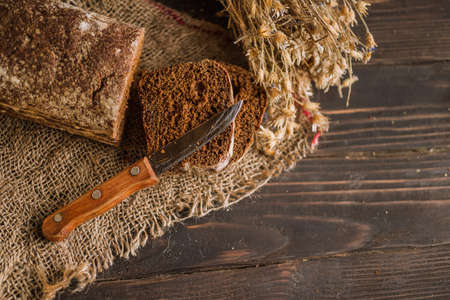 Dark multigrain cereal bread on rustic wooden boardの写真素材