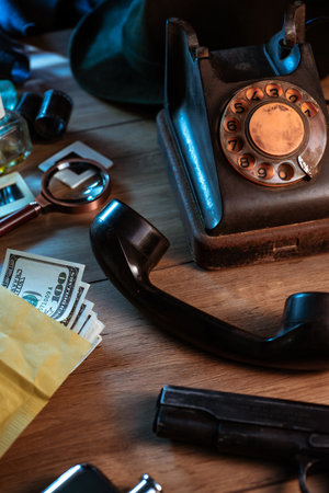 Private detective's desk, noir still life with a vintage phone, typewriter, lamp, gun and retro photosの写真素材