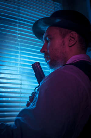 Suspicious private detective near the window with blinds, cinematic noir sceneの写真素材