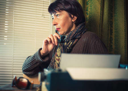 Vintage female writer reporter working behind his deskの写真素材