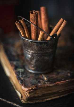 Tiny rusty bucket with cinnamon sticks on rustic wooden backgroundの写真素材