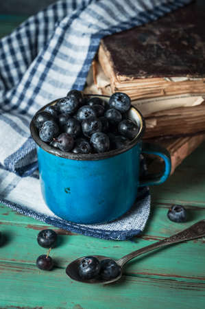 Blue vintage iron cup with blueberries on rustic backgroundの写真素材