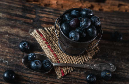 Tiny bucket with blueberries on rustic wooden background