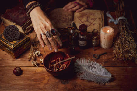 Female witch making potion on dark background, magic bottles with potions and candles on table of alchemist, Halloween themeの素材 [FY310174990453]