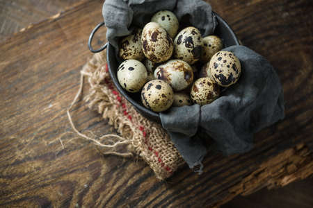 Raw quail eggs in egg box on rustic wooden background