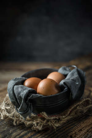 Raw eggs in egg box on rustic wooden background