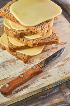 Sliced pieces of cheese on rustic wooden background, cheese sandwichesの写真素材