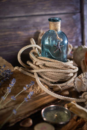 A marine concept with a bottle, starfish, seashells, rope, compass and paper scroll, pirate still lifeの写真素材