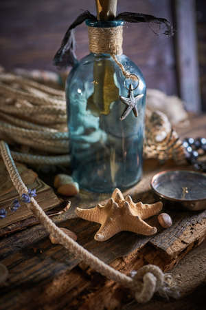A marine concept with a bottle, starfish, seashells, rope, compass and paper scroll, pirate still lifeの写真素材