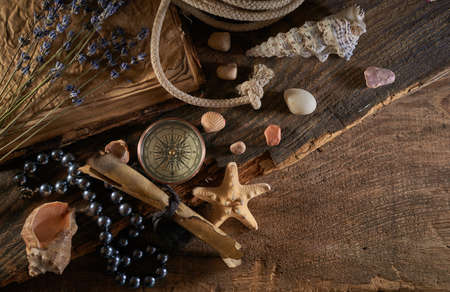 A marine concept with a bottle, starfish, seashells, rope, compass and paper scroll, pirate still lifeの写真素材