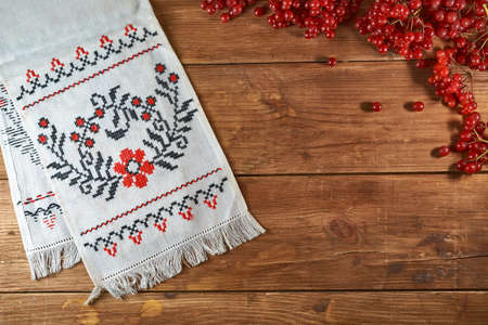 Ukrainian still life with traditional elements: flag of Ukraine, national embroidery and viburnum berries on a wooden backgroundの写真素材