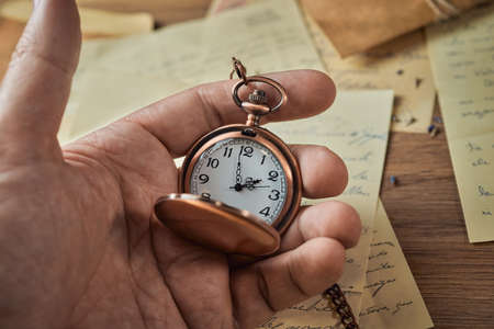 Vintage writing utensils on a wooden table, old watch, papers, letters, envelopes and scissors