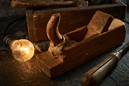 Wooden tool box of used hand tools with old and dirty, rusty wrenches, hammers, and old light bulb