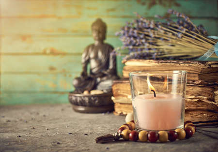 Spiritual still life with candles, beads, statue of Buddha and dry flowersの写真素材