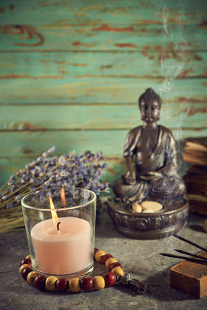 Spiritual still life with candles, beads, statue of Buddha and dry flowersの写真素材